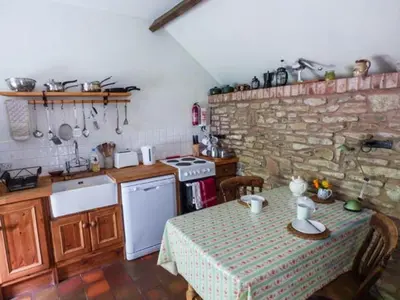 a kitchen with a table and a stone wall at The Smithy in Leominster