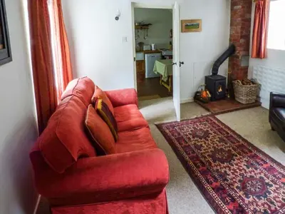 a living room with a red couch and a fireplace at The Smithy in Leominster