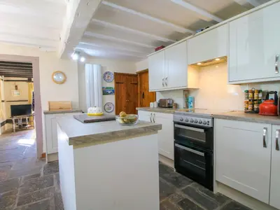 a kitchen with white cabinets and a black oven at Callow Cottage in Craven Arms