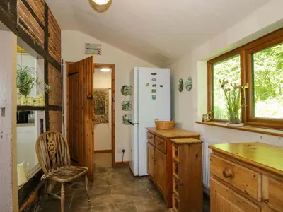 a kitchen with a refrigerator and a chair in it at Callow Cottage in Craven Arms