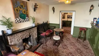 a living room with a fireplace and a table and chairs at Community Owned Gwesty Owain Glyndwr Hotel in Corwen