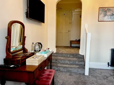 a hallway with a dresser and a mirror and stairs at Community Owned Gwesty Owain Glyndwr Hotel in Corwen