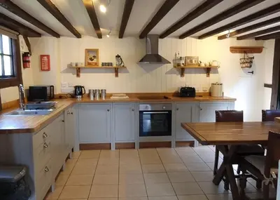 a kitchen with white cabinets and a wooden table at The Wain House at Brinsop in Hereford
