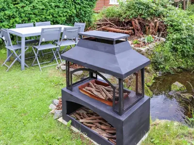 a charcoal grill in a garden with a table and chairs at Barken in Trawsfynydd