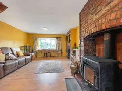 a living room with a brick fireplace and a couch at Swan Cottage in Carrog
