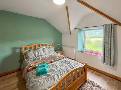a bedroom with a bed and a window at Swan Cottage in Carrog