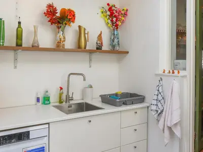 a kitchen counter with a sink and flowers on shelves at Crescent Cottage in Newtown