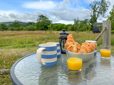 a table with a tray of bread and cups of orange juice at The Sheep Pod - Uk50074 in Welshpool