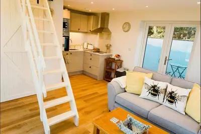 a living room with a couch and a ladder at Honey Bee Cottage Tiny House Welshpool in Welshpool