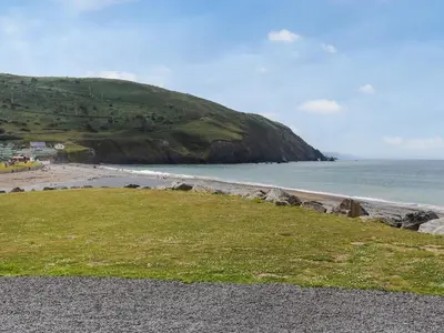 a beach with a grass field and the ocean at The Laughing Seagull - Uk50213 in Aberystwyth