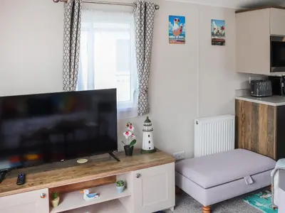 a living room with a flat screen tv on a wooden entertainment center at The Laughing Seagull - Uk50213 in Aberystwyth