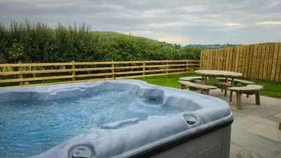 a hot tub in a backyard with a picnic table at Daverneithon 3 in Rhayader