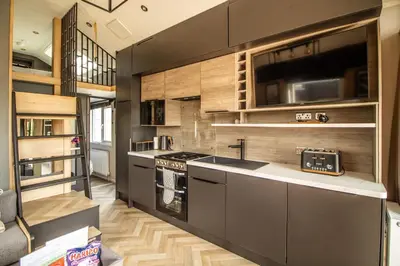 a kitchen with stainless steel appliances and wooden walls at Daverneithon 2 in Rhayader