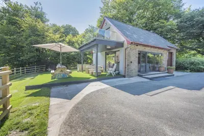 a small house with a patio and an umbrella at 2 Bed in Llanybydder oc-b32255 in Cwrt-newydd