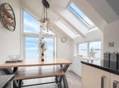 a dining room with a table and windows at Sailhouse Loft New Quay in New Quay