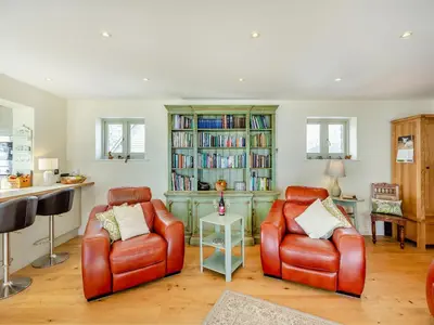 a living room with two chairs and a book shelf at Orchard Barn in Llandrindod Wells