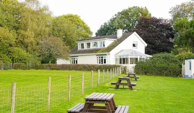 a white house with picnic tables in the yard at Five Oaks B&B - New Quay in Llanina