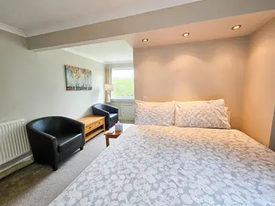 a bedroom with a bed and a chair at Five Oaks B&B - New Quay in Llanina