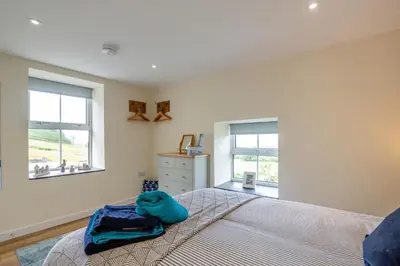 a bedroom with a bed and two windows at 3 Bed in Tywyn oc-b32570 in Llangelynin