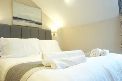 a bedroom with a white bed with towels on it at The Barmouth Bar & Grill in Barmouth