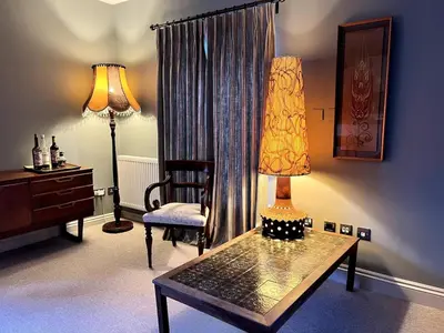 a living room with a table and a lamp and a chair at Rooftops in Hay-on-Wye