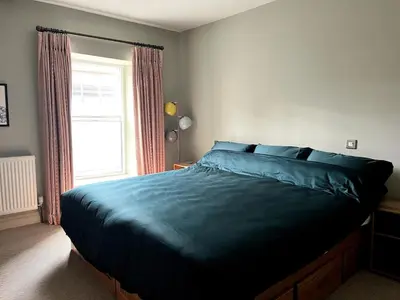 a bedroom with a bed with blue sheets and a window at Rooftops in Hay-on-Wye