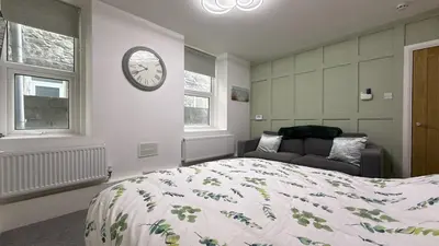 a bedroom with a bed and a clock on the wall at Barmouth Beach Ground Floor Studio in Barmouth