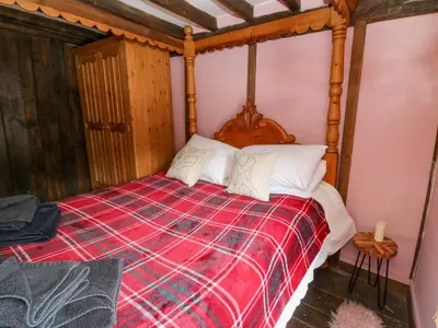 a bedroom with a bed with a red blanket at The Little Laura Ashley House in Machynlleth