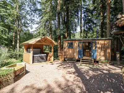 a cabin in the woods with a tent at Tanglewood Shepherds Hut in Welshpool