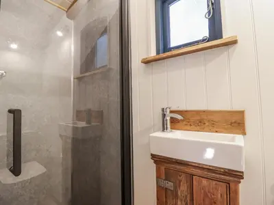 a bathroom with a sink and a shower at Tanglewood Shepherds Hut in Welshpool