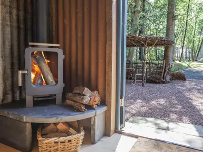 a wood fired stove in a building with a porch at Tanglewood Shepherds Hut in Welshpool