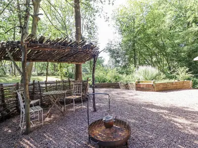 a pergola and table with a vase on top of it at Tanglewood Shepherds Hut in Welshpool
