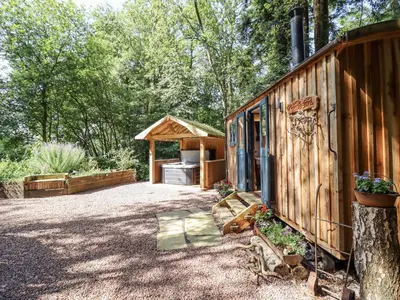 a cabin in the woods with a gazebo at Tanglewood Shepherds Hut in Welshpool