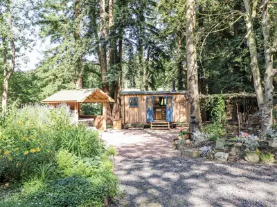 a log cabin in the woods with a gazebo at Tanglewood Shepherds Hut in Welshpool