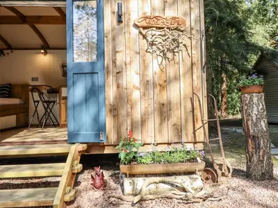 a wooden privacy fence with a flower garden on a porch at Tanglewood Shepherds Hut in Welshpool