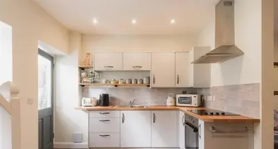 a kitchen with white cabinets and a stove top oven at Vern Dale Cottage, Erwood, River Wye, Builth Wells in Builth Wells