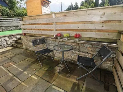 a patio with a table and two chairs and a fence at Vern Dale Cottage, Erwood, River Wye, Builth Wells in Builth Wells