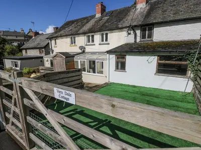 a house with a sign on a wooden fence at Vern Dale Cottage, Erwood, River Wye, Builth Wells in Builth Wells