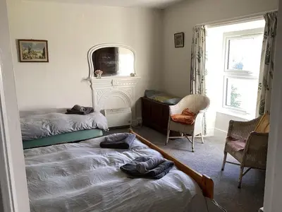 a bedroom with two beds and a chair and a window at Large farmhouse in Snowdonia, North Wales in Talsarnau