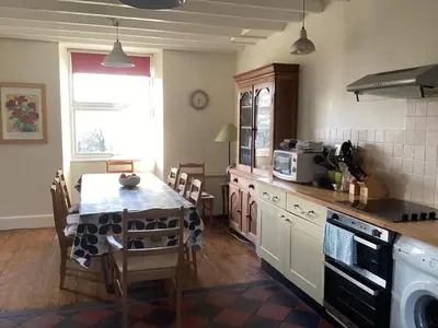 a kitchen with a table and a dining room at Large farmhouse in Snowdonia, North Wales in Talsarnau