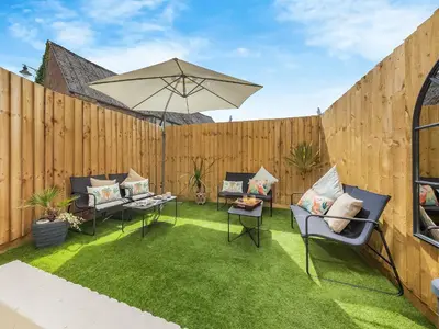a patio with chairs and an umbrella on the grass at Lansdowne House in Brecon
