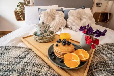 a breakfast tray with pancakes and oranges on a bed at Wyns Barn in Rhayader