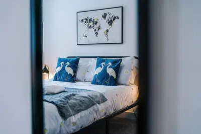 a bedroom with a bed with blue pillows and a map at Double the Comfort - 2 Hansas Luxury & Spacious Townhouses by Parydise Properties - Ideal for Business or Family in Harlescott