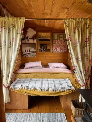 a small bed in a room with curtains at Black Bridge Cabin in Lyonshall