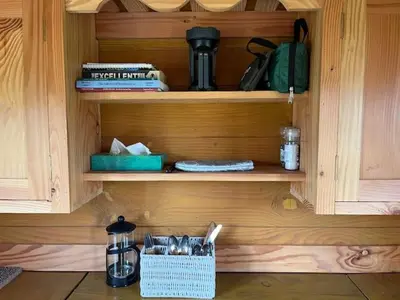 a wooden cupboard with a coffee maker and a basket at Black Bridge Cabin in Lyonshall