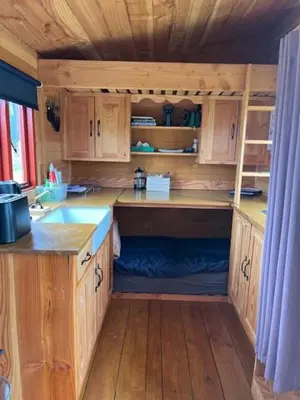 a small kitchen with wooden cabinets and a sink at Black Bridge Cabin in Lyonshall