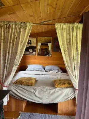 a bed with curtains and pillows in a room at Tick Bridge cabin in Lyonshall