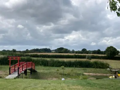 a red bridge over a river in a field at Tick Bridge cabin in Lyonshall