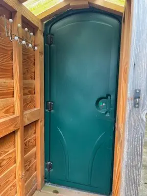 a green door in a room with wooden cabinets at Tick Bridge cabin in Lyonshall