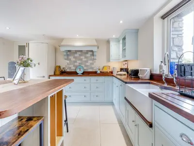a kitchen with white cabinets and wooden counter tops at Hays Boathouse-Maes-Y-Caer in Hay-on-Wye